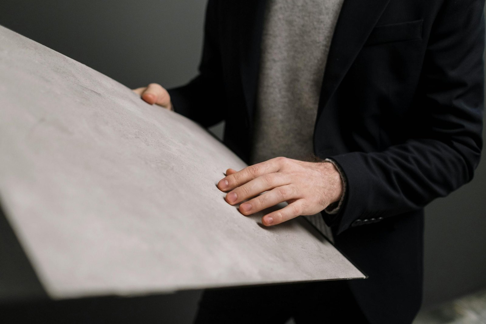 Close-up of a man in business attire examining a large gray panel indoors.