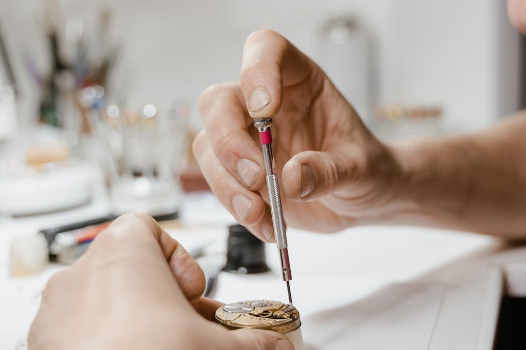 Close-up view of hands using screwdriver for detailed wristwatch repair.