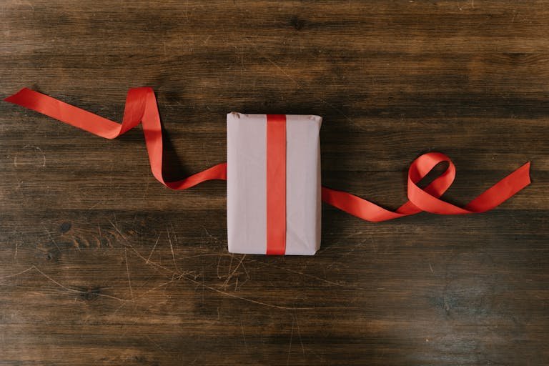 Elegant gift wrapped with red ribbon on a rustic wooden surface, perfect for holidays.